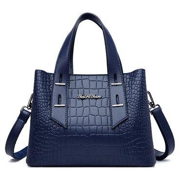 Blue handbag with crocodile texture and visible brand name on a white background
