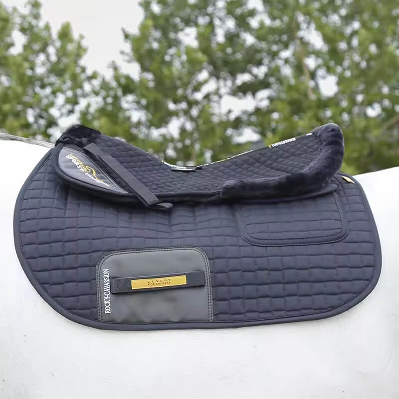Navy blue quilted saddle pad on a white surface with trees in the background