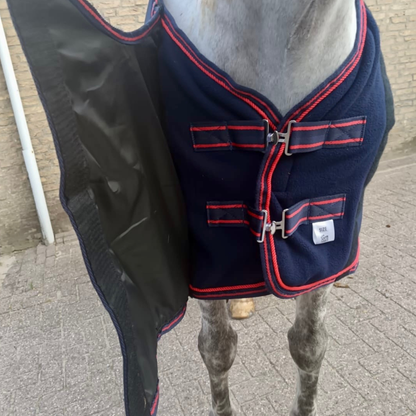 Navy blue horse blanket with red trim on a horse