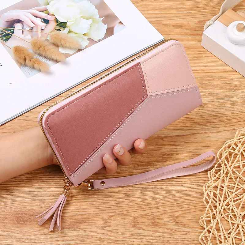 Pink women's patchwork zip wallet with tassel zipper pull in hand